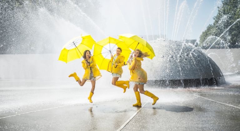 A Group Of People In Yellow Raincoats Holding Umbrellas