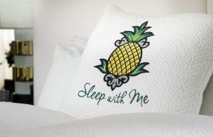 Sleep with me logoed pillow on guestroom bed